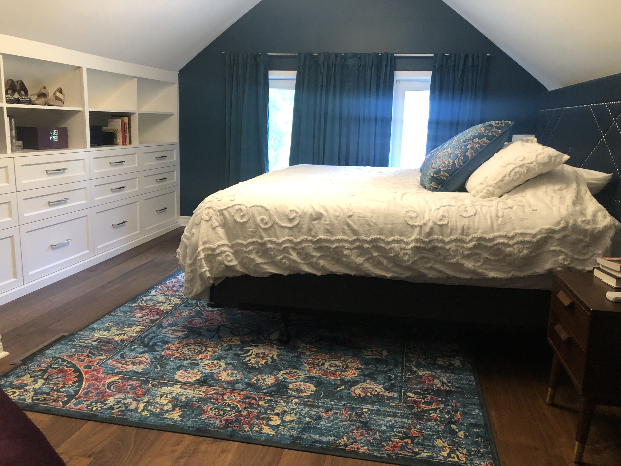 master bedroom featuring colourful rug and built in wall shelving